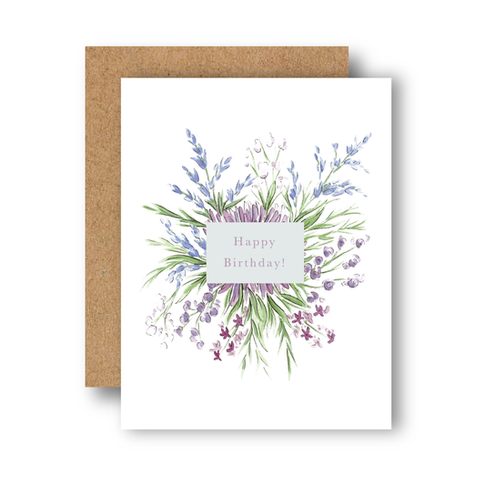 White birthday card with purple and blue watercolor flowers, green leaves, and ‘Happy Birthday!’ over a kraft envelope.
