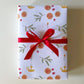 Gift box wrapped in festive paper with a red ribbon on a light background