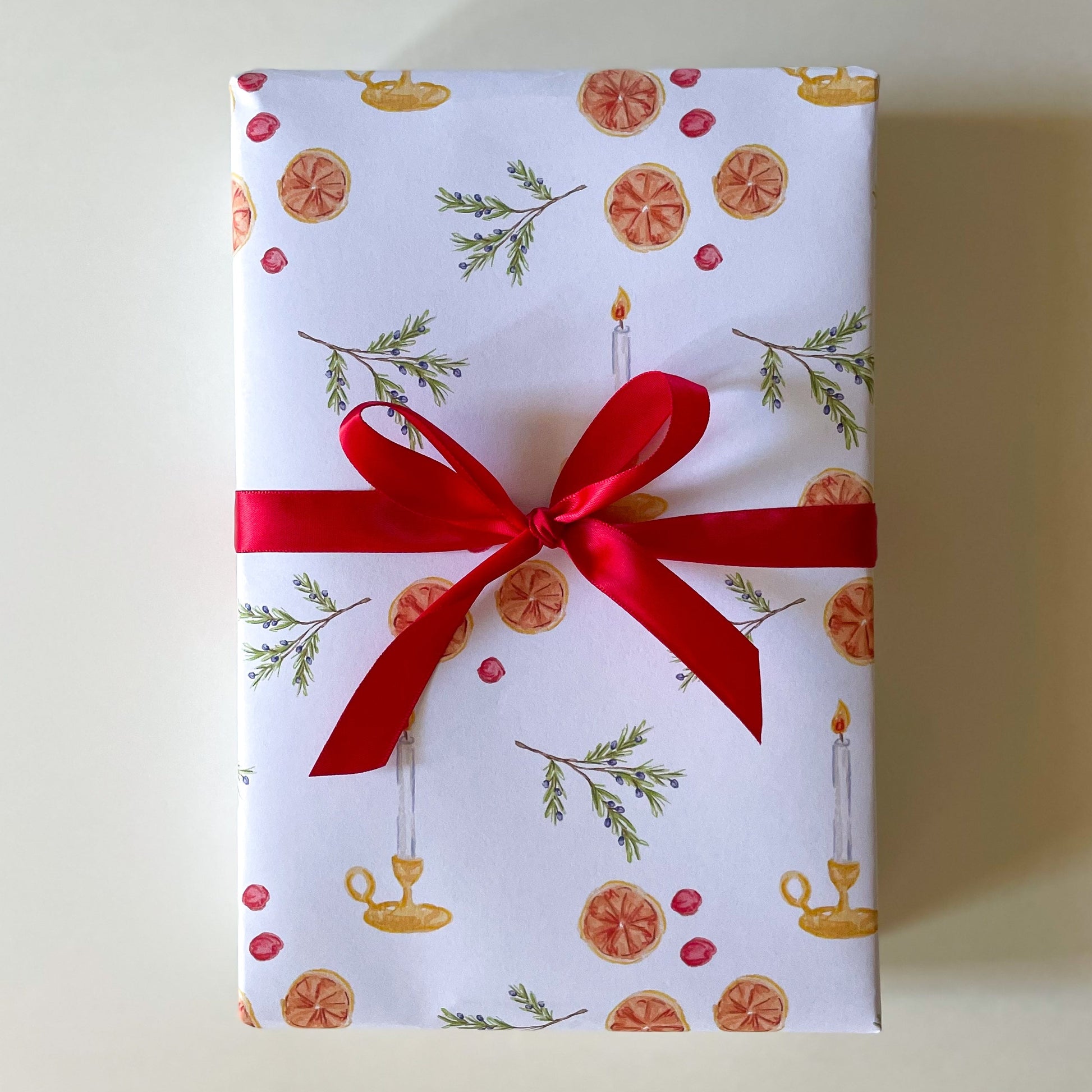 Gift box wrapped in festive paper with a red ribbon on a light background